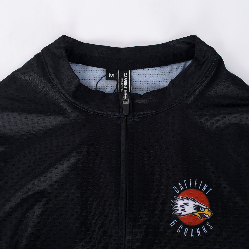 Close-up of C&C Tattoo Eagle Jersey: Black with red/white eagle logo and orange sun emblem.