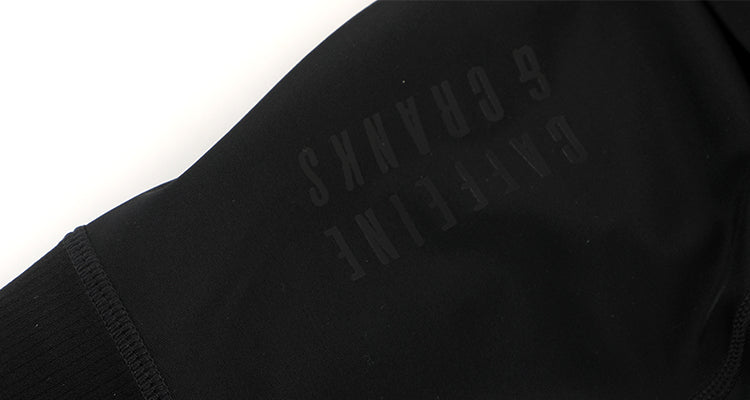 Closeup of mens black cargo bib shorts with subtle tonal logo.