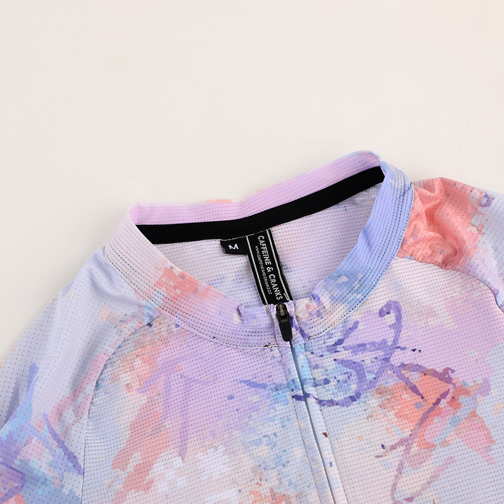 Close-up of a C&C Vapour Jersey in white with a watercolor splash print in pink, purple, and blue.