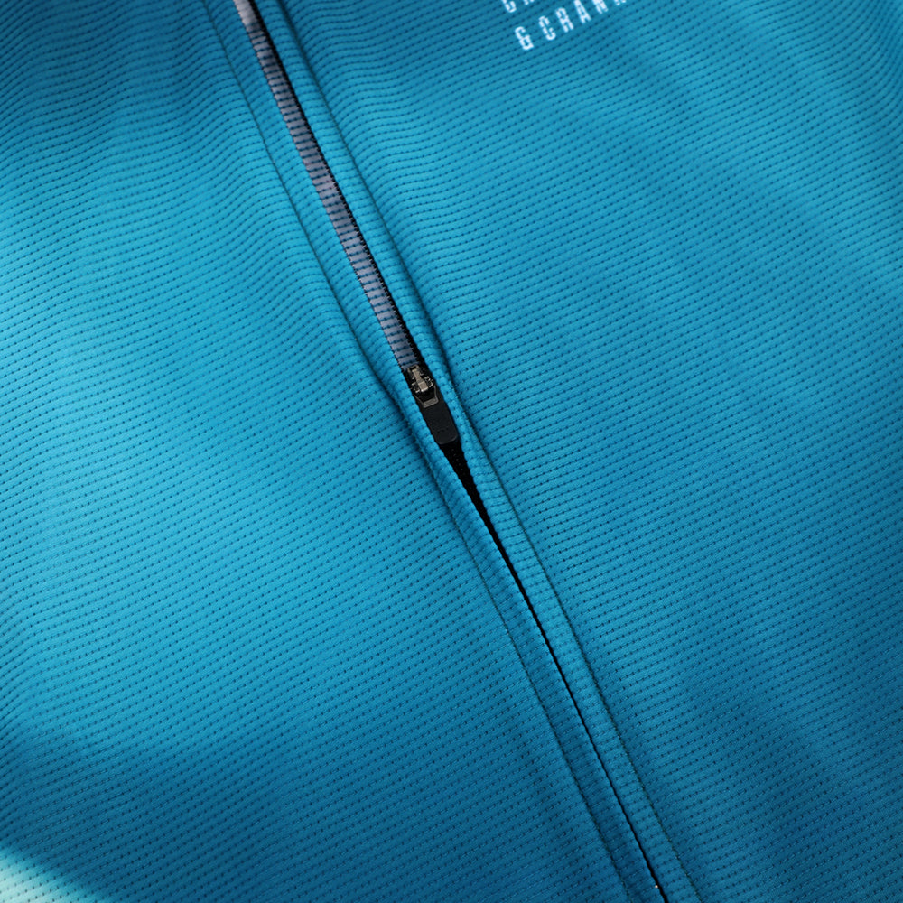 Close-up of a men's C&C Flux Jersey in teal blue, showing the textured fabric and zipper.