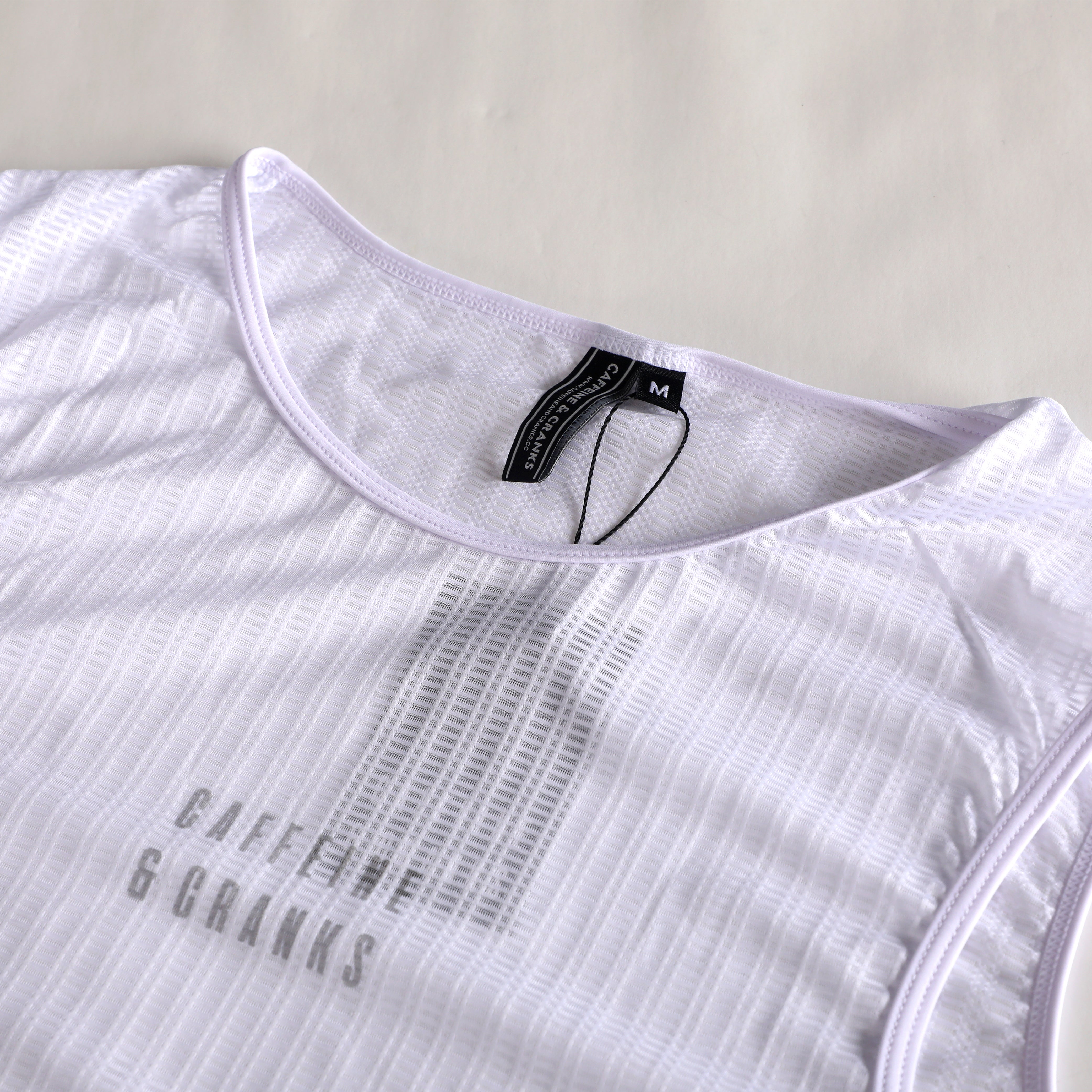 Close-up of white C&C Core Baselayer for men, showing textured fabric and logo.