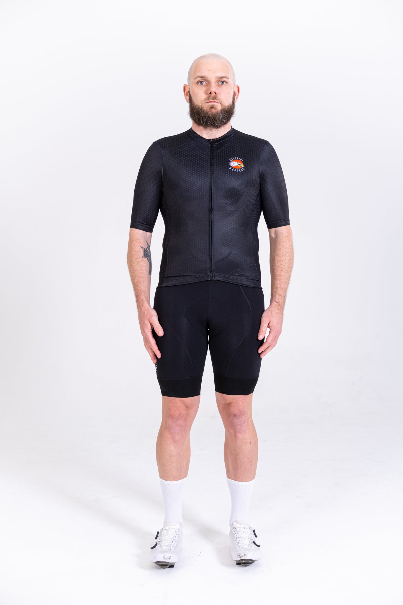 Full body shot of a man in a black C&C Tattoo Series mens jersey with orange sun logo & black shorts.