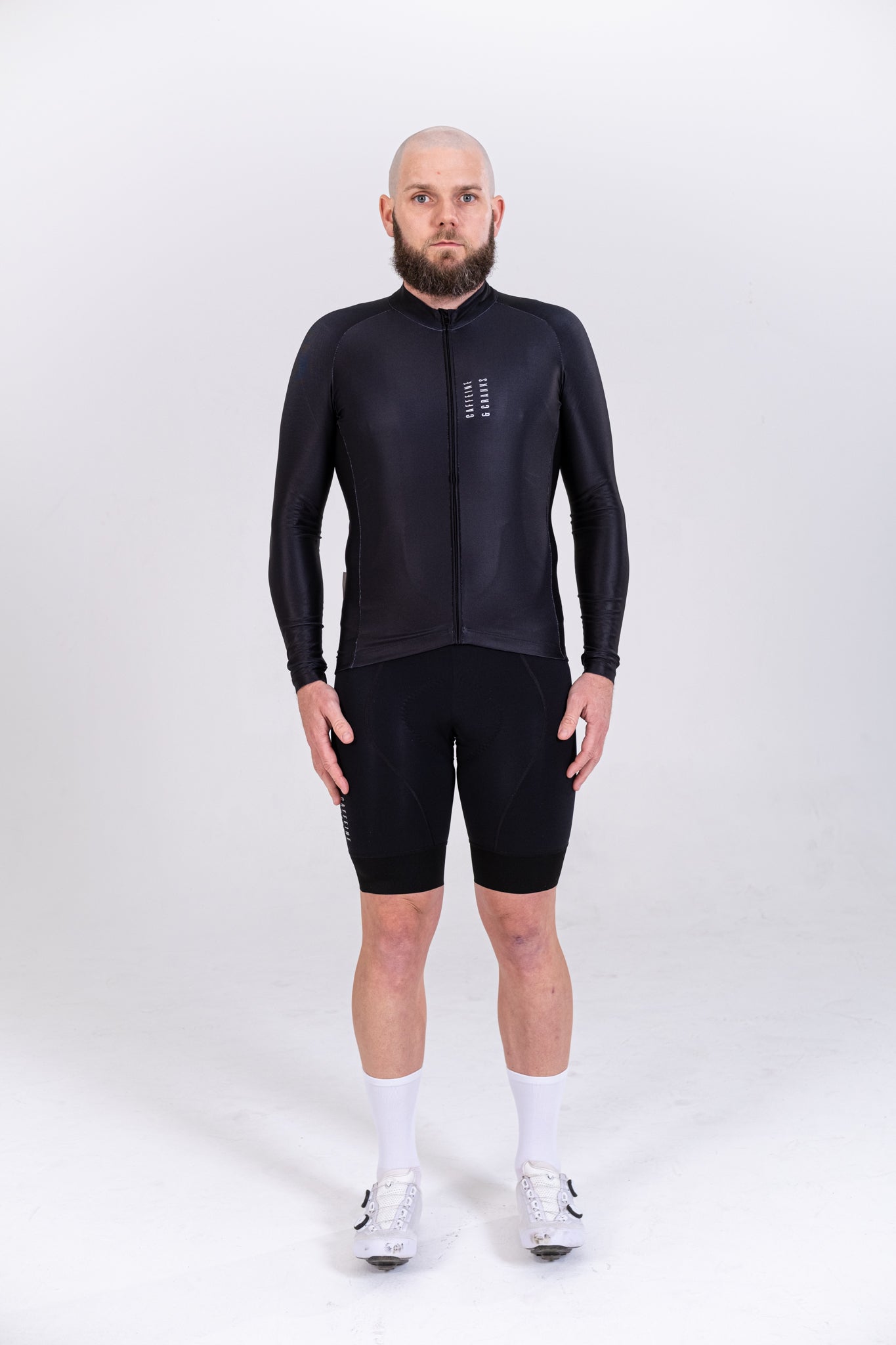 Front view of male model wearing a black long-sleeve Core Thermal Jersey and black cycling shorts.