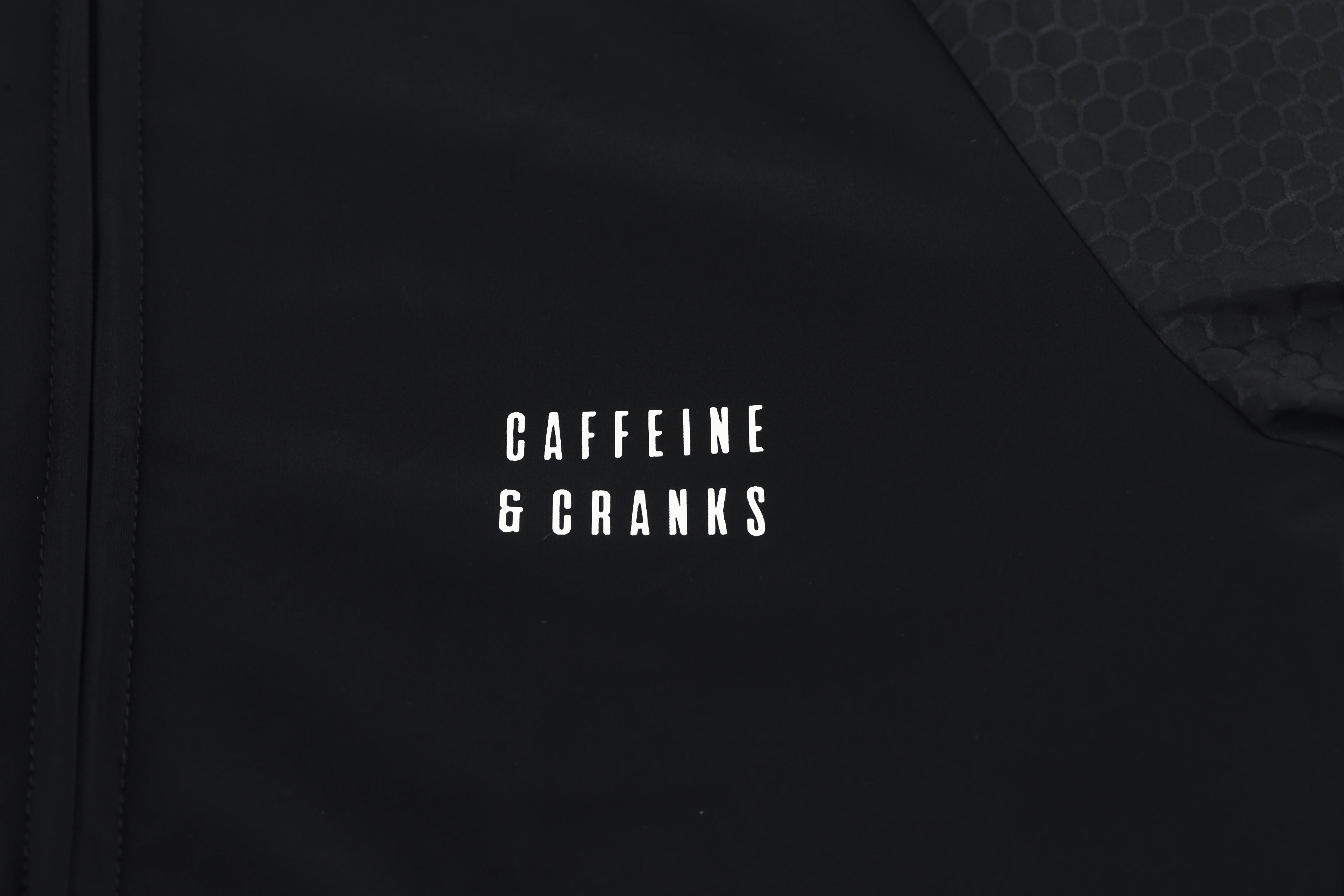 Close-up of a black women's Pinnacle Jersey with "Caffeine & Cranks" logo and honeycomb texture.