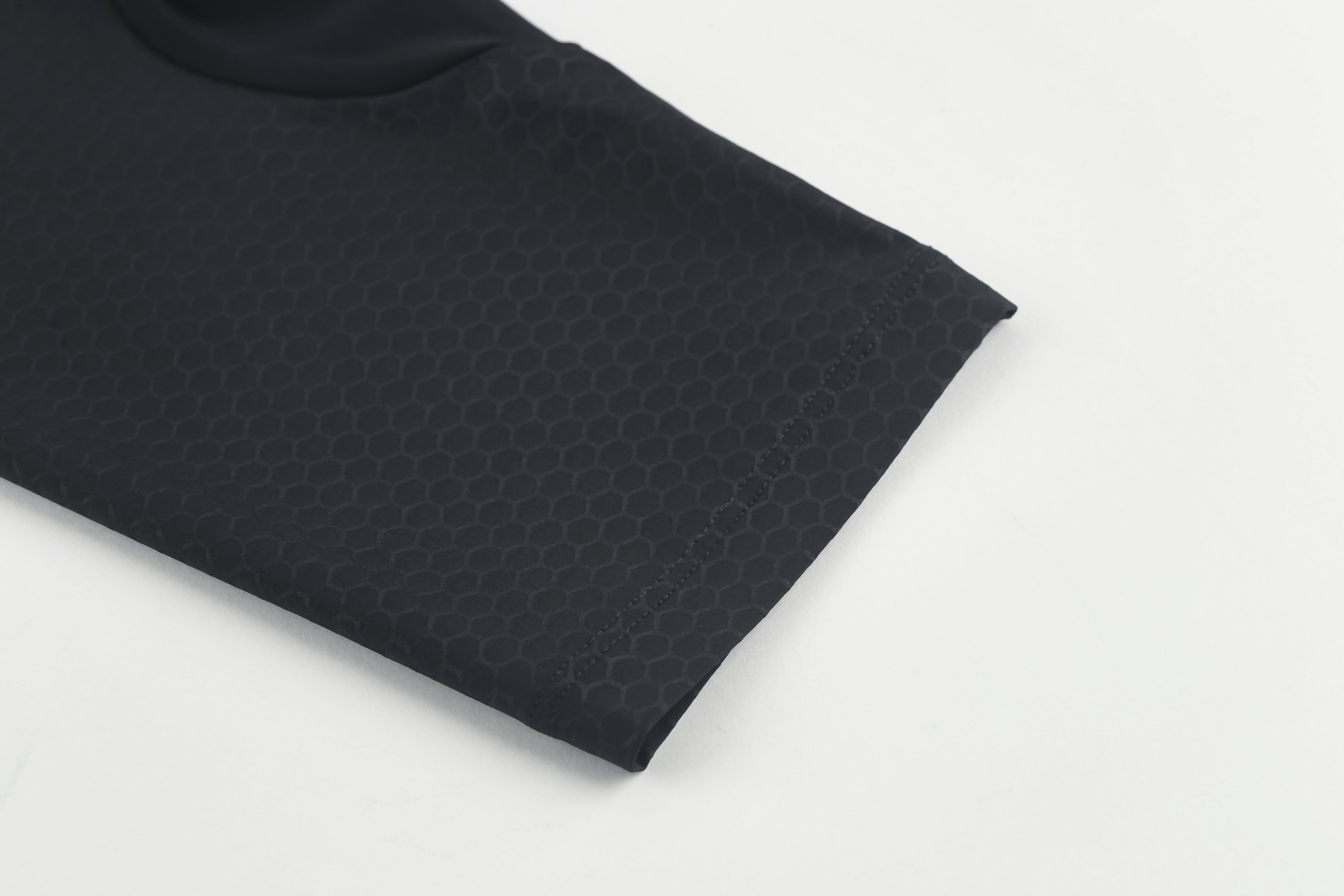 Close-up of a black women's jersey sleeve with a subtle honeycomb texture.