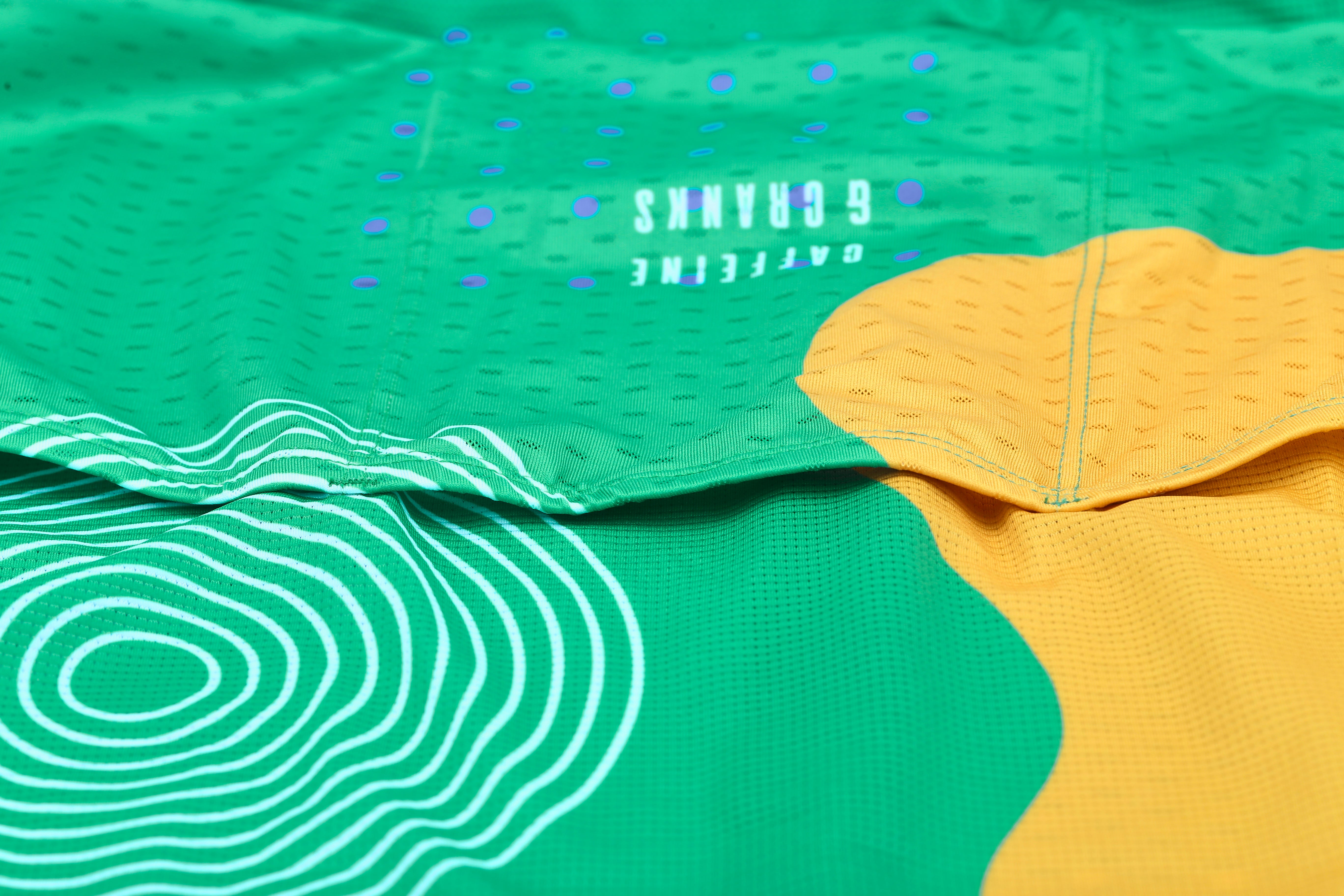 Close-up of C&C Memphis Bright Jersey - green with white wave pattern, yellow section, and blue dots.