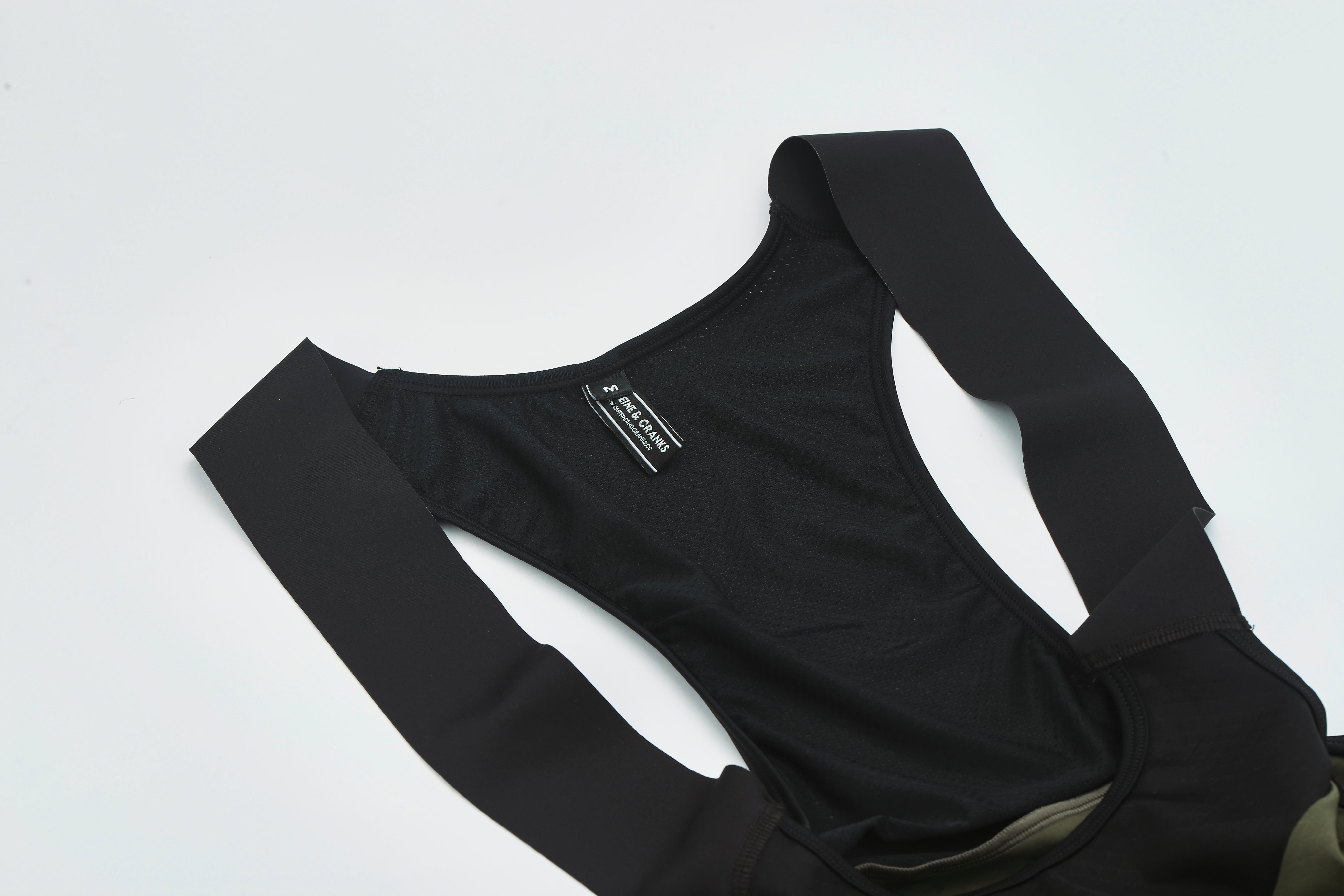 Close-up of women's black bib shorts with olive green panels and textured fabric.