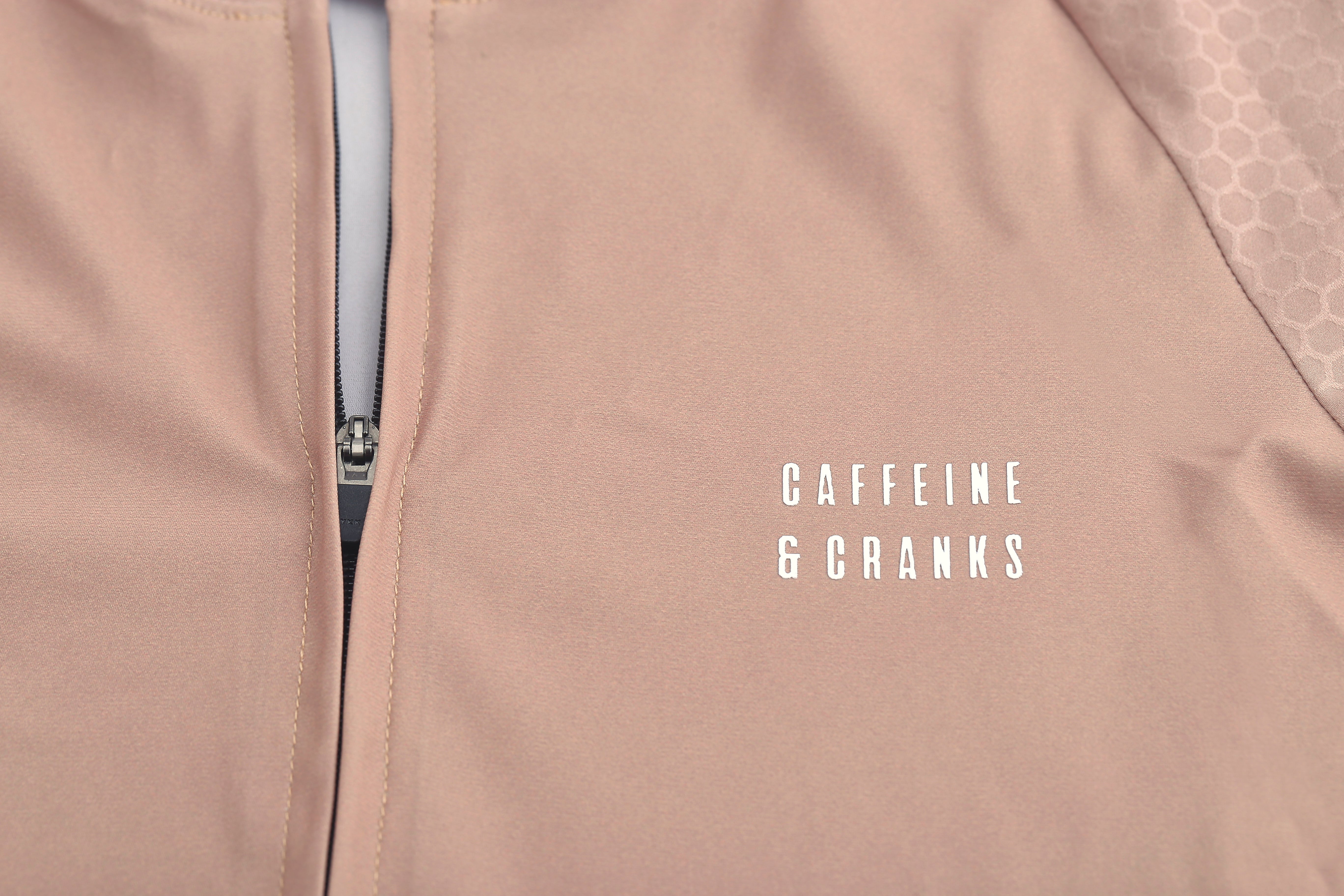 Close-up on a clay-colored mens Pinnacle Jersey with a zippered front and subtle honeycomb pattern on the sleeve.