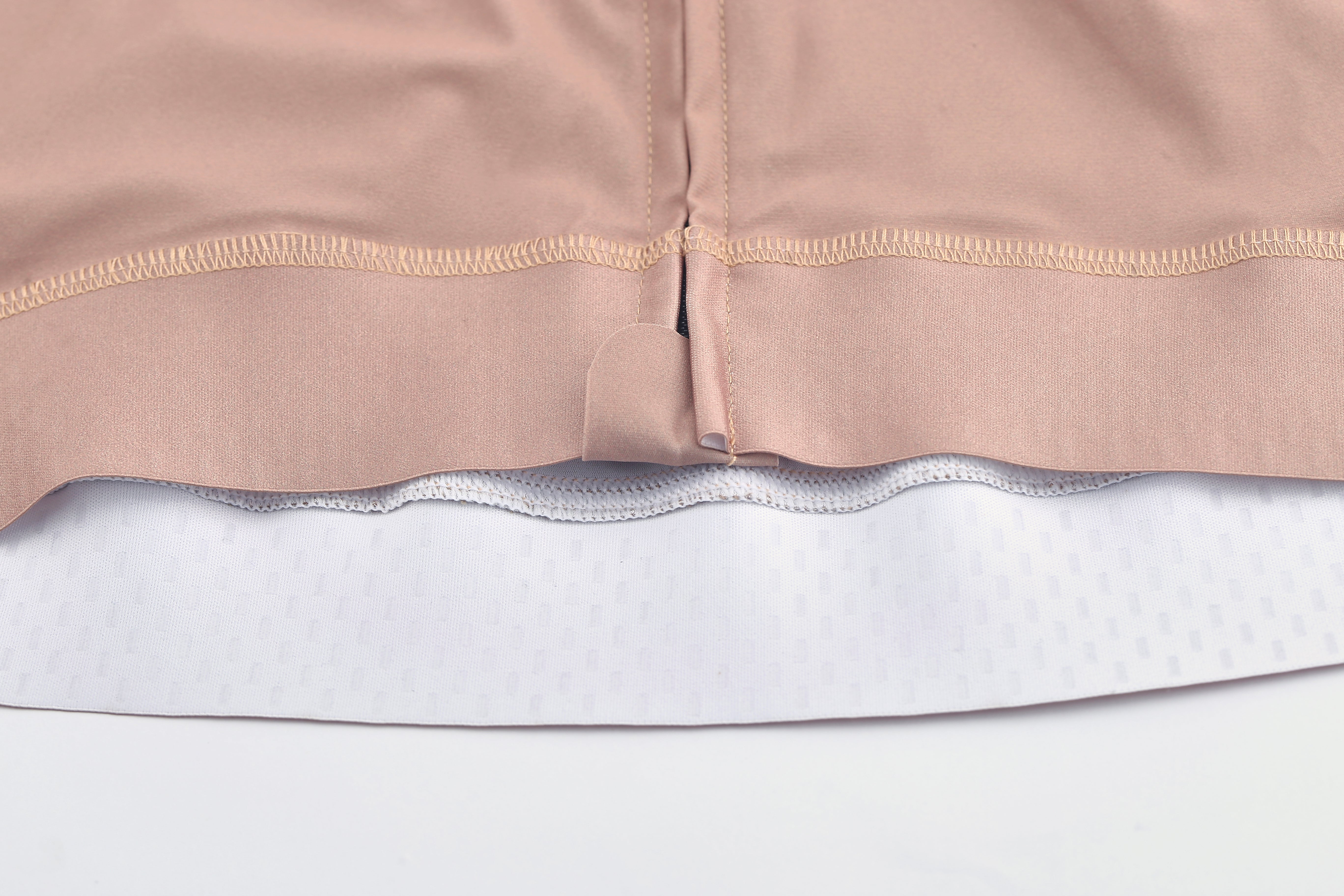 Close-up of a clay pink Pinnacle Jersey hem with white textured fabric underneath.