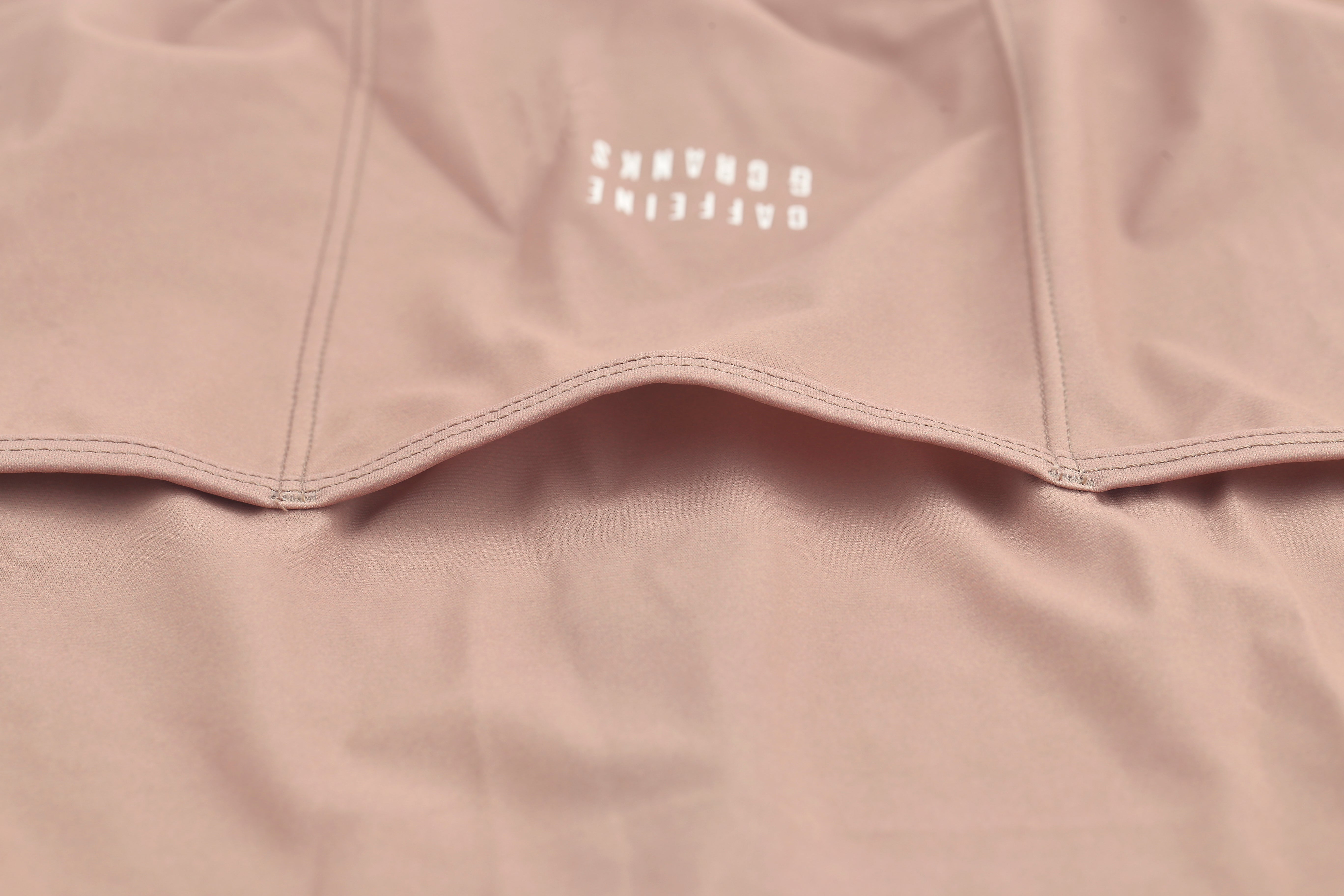 Detailed crop of the Clay Pinnacle Jersey for men, showing the clay color fabric with white logo and textured stitching.