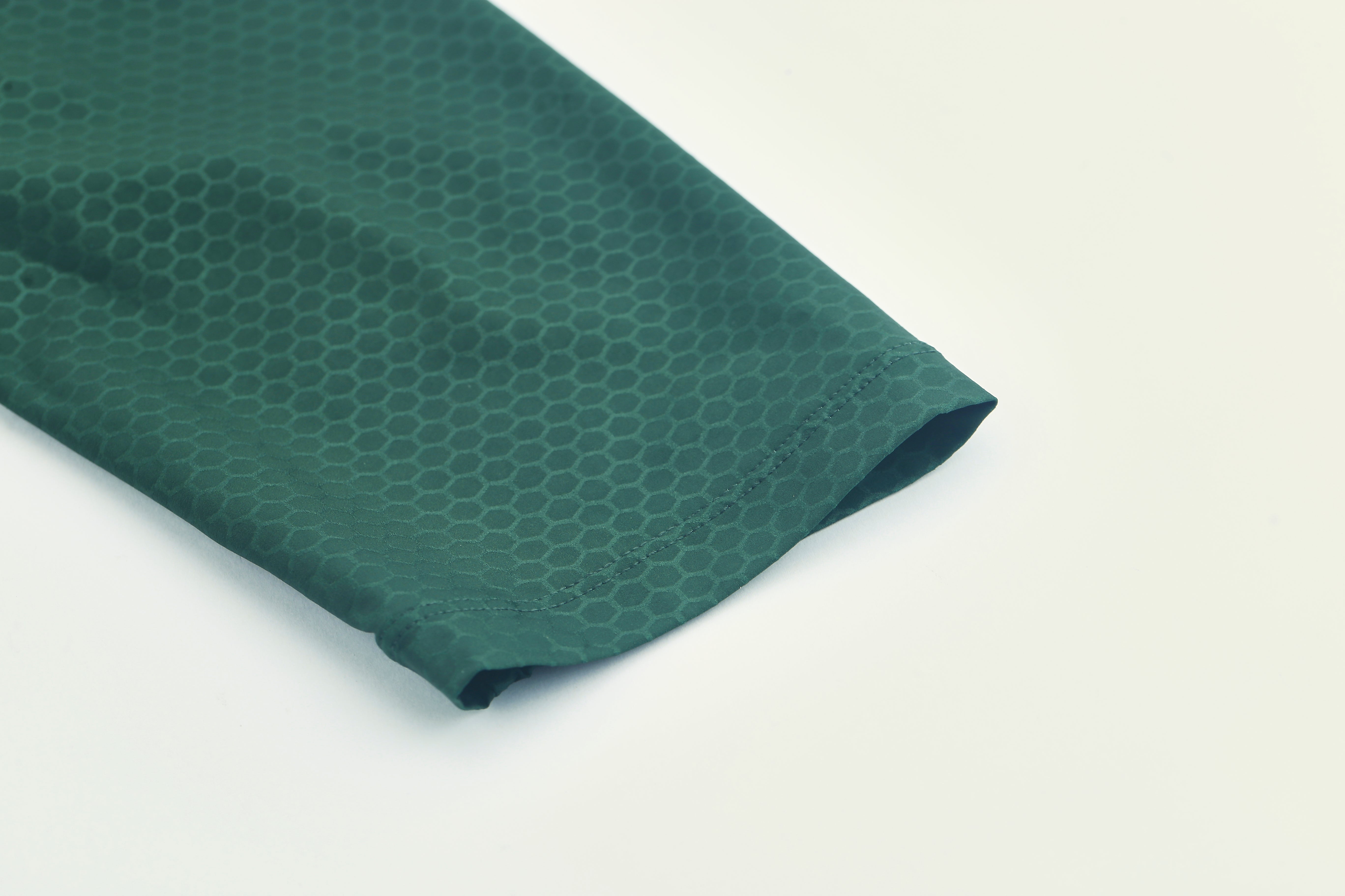 Close-up of the sleeve hem of a women's green Pinnacle Jersey with a subtle honeycomb pattern.
