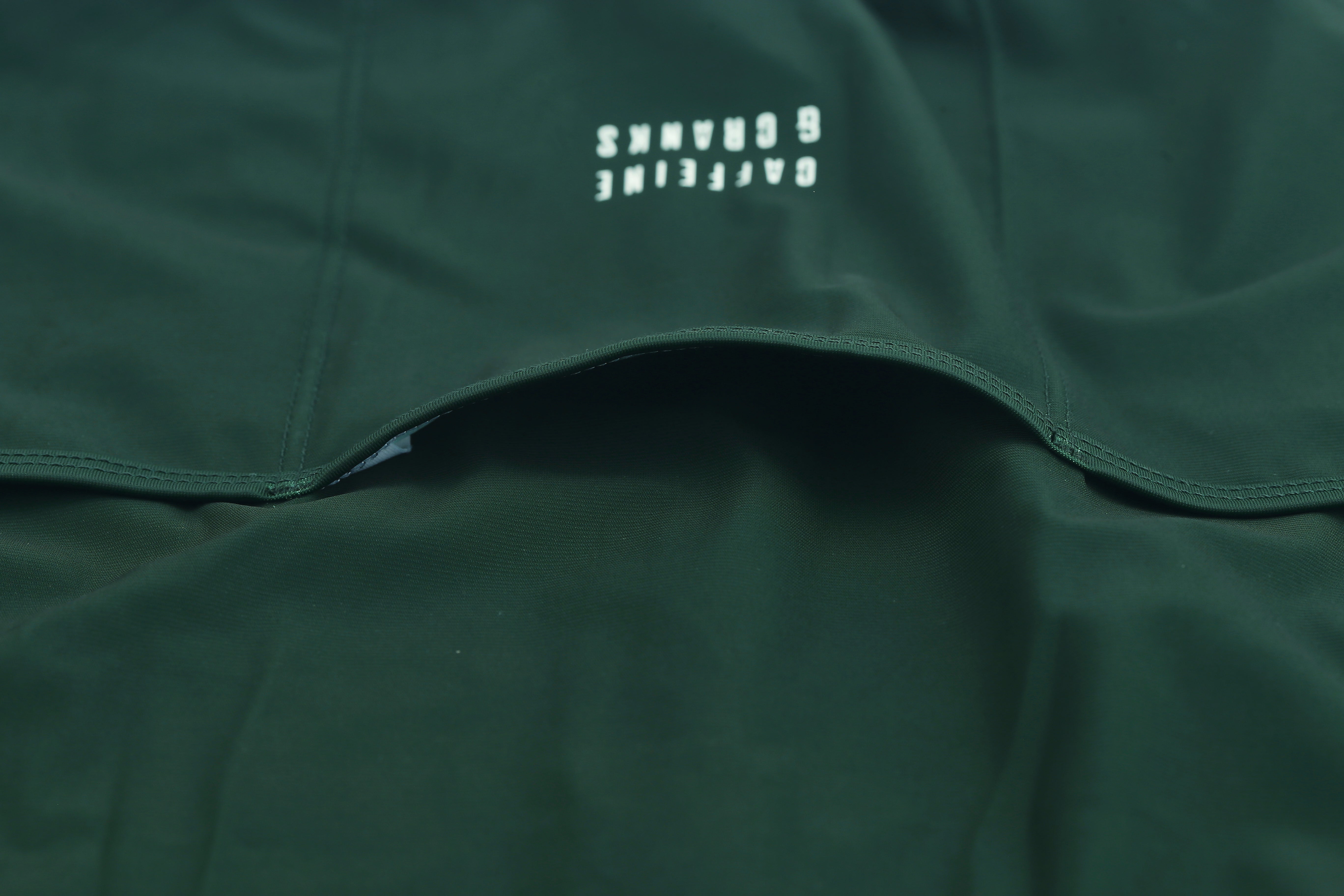 Close up of forest green Pinnacle Jersey for men. Features an open pocket with white logo detailing.