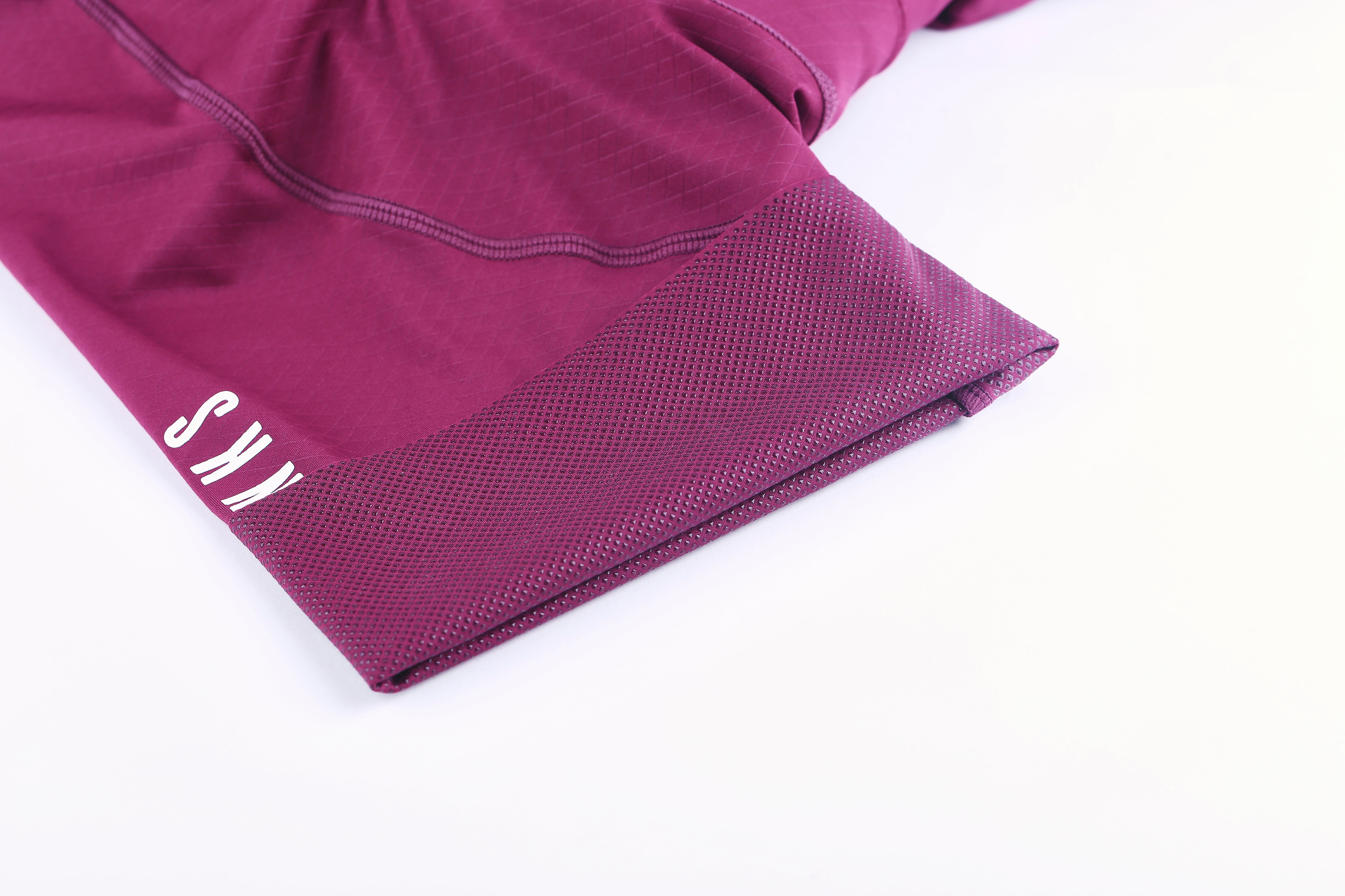 Detailed view of men's royal red bib shorts leg opening showing gripper dots & white logo.