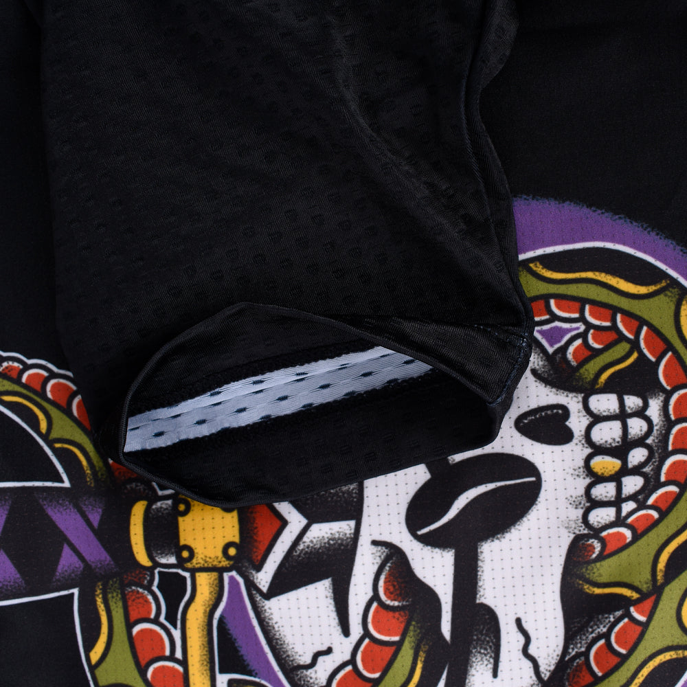 Close-up of C&C Tattoo Series Skull Jersey sleeve cuff. Black fabric, skull & snake tattoo design, purple, green, red, yellow.