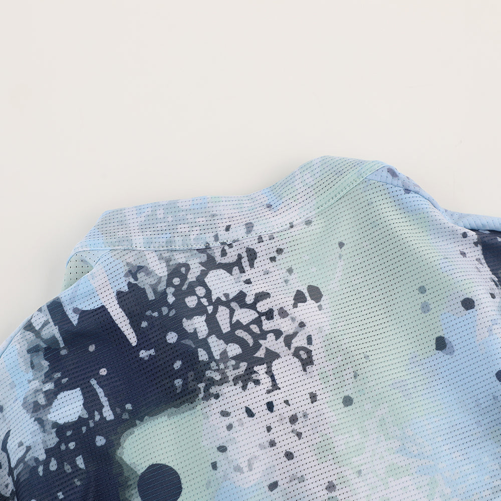 Close-up of C&C Overspray Jersey Women's collar and shoulder. Features a mesh fabric with blue, green, and white abstract spray paint print.