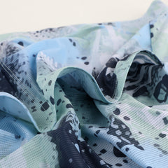 Close-up of C&C Overspray Jersey showing blue & green abstract pattern with dark spots.