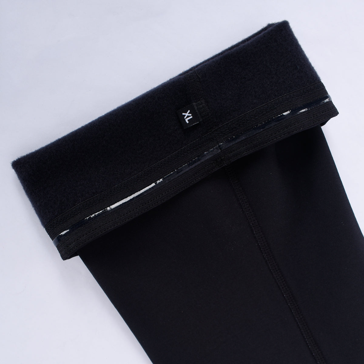 Close-up of black thermal leg warmers, size XL, with fleece lining and elastic band.