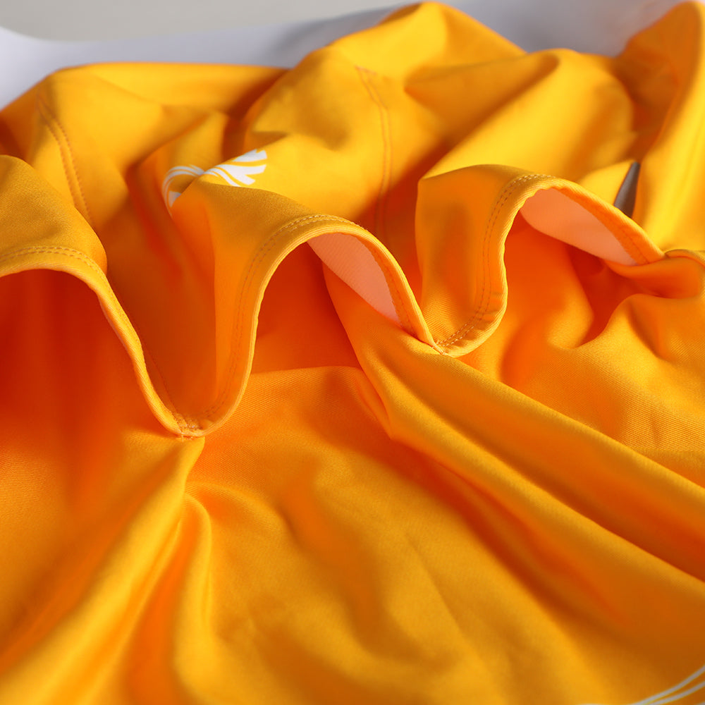 Close-up, wrinkled yellow women's thermal jersey with white logo detail.