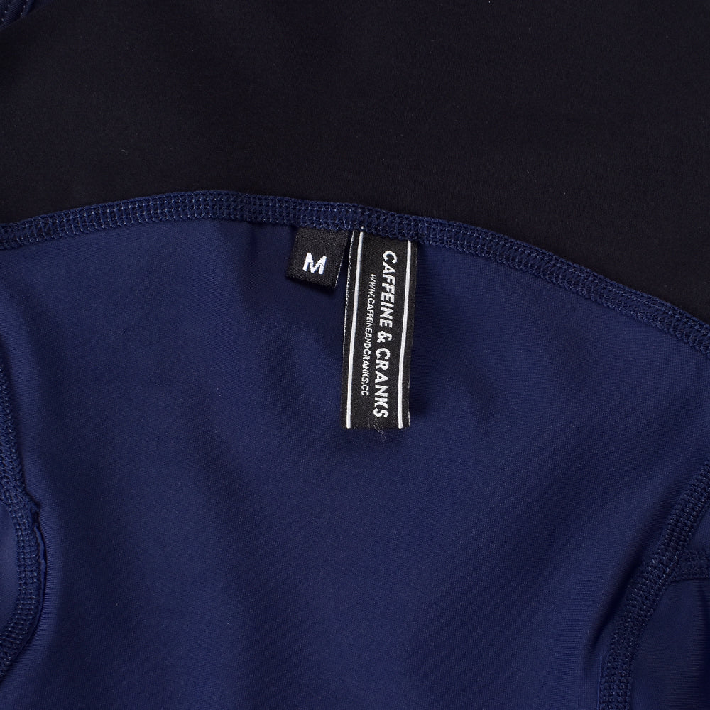 Close-up of navy Core Bib Shorts showing size M tag and black waistband detail.