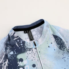 Close-up of C&C Overspray Jersey for women, featuring blue, white, and gray splatter print & full zip.