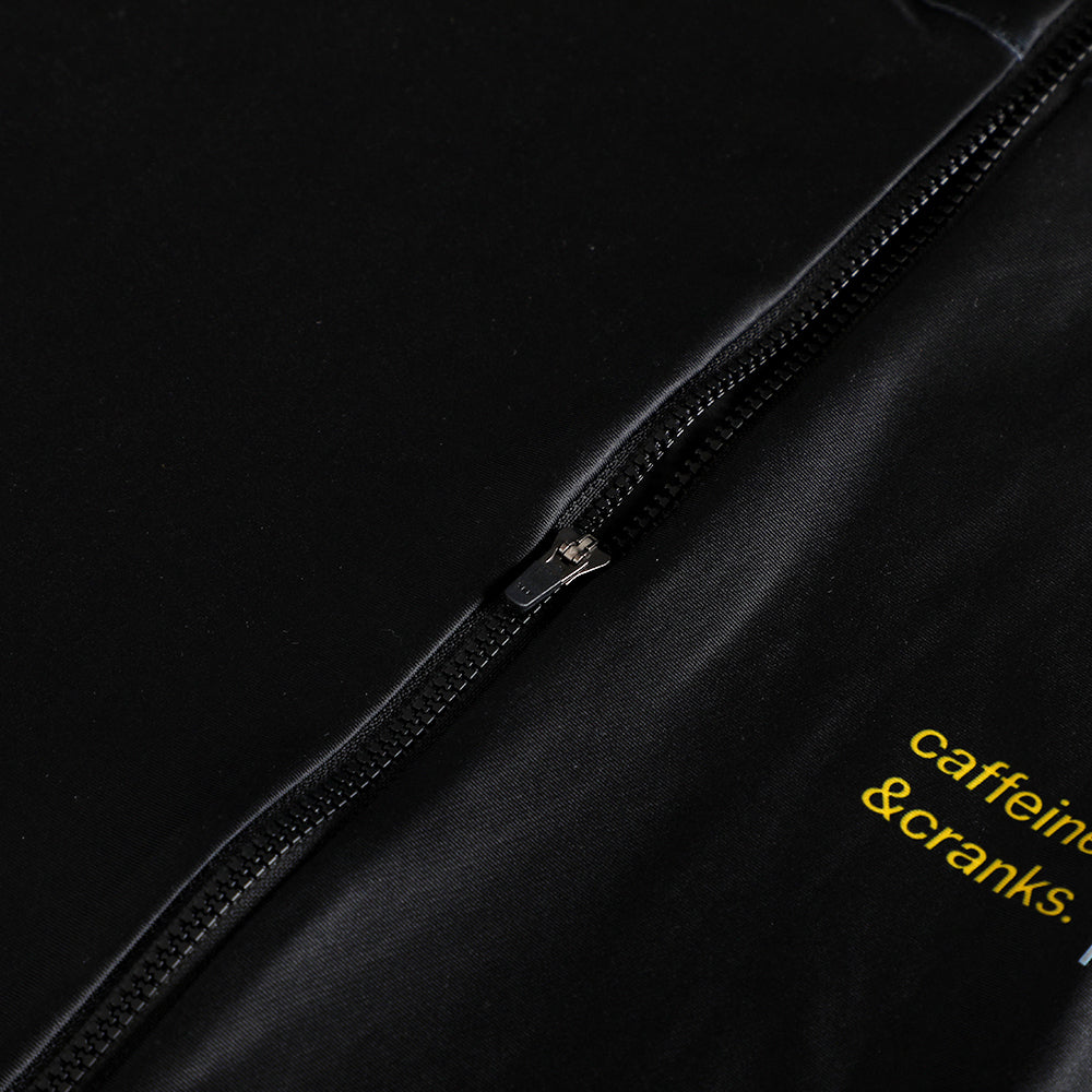 Close-up of black thermal jersey with yellow text and a metal zipper detail.