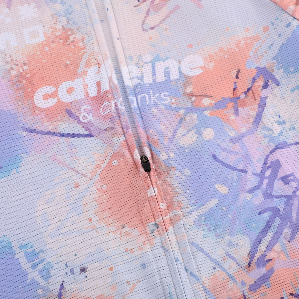 Close-up of C&C Vapour Jersey showing pink, purple, and blue paint splatters and a zipper.