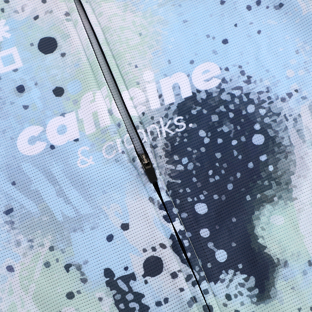 Close-up of men's C&C jersey zipper, featuring abstract blue, white, & black overspray design.