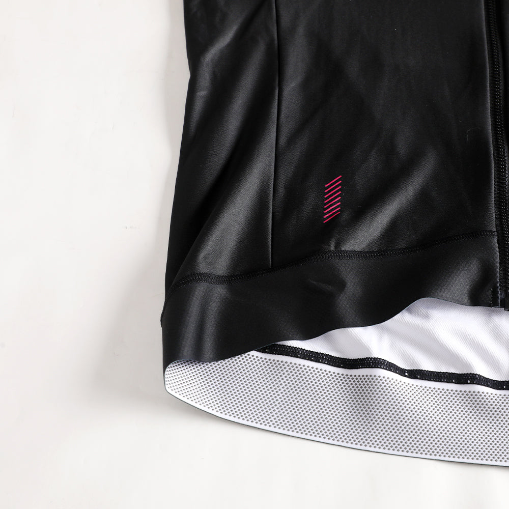 Close-up of black Pinnacle Thermal Jersey hem with pink stripe detail & mesh lining.