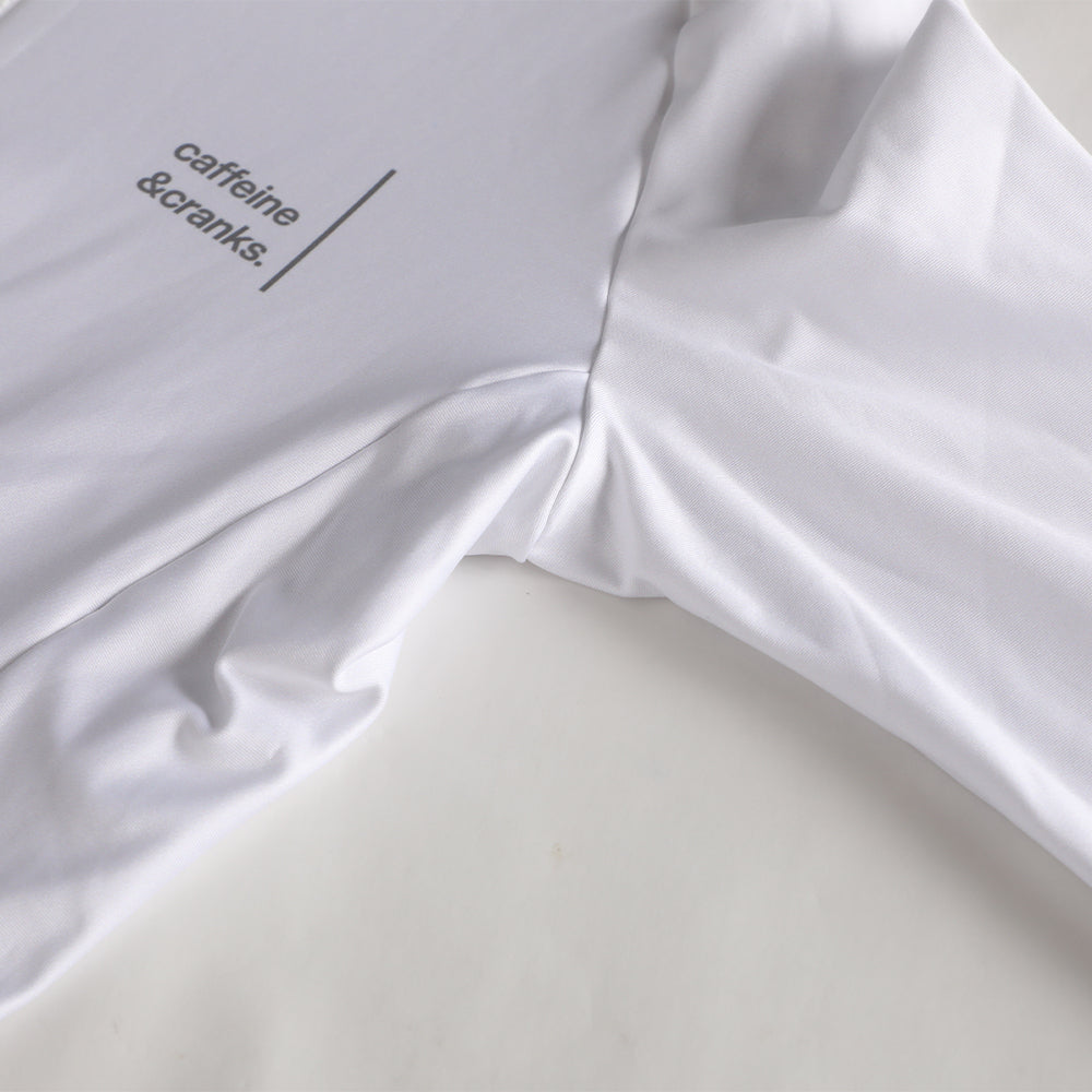 Close-up of white women's thermal jersey with grey "caffeine & cranks" logo on sleeve.