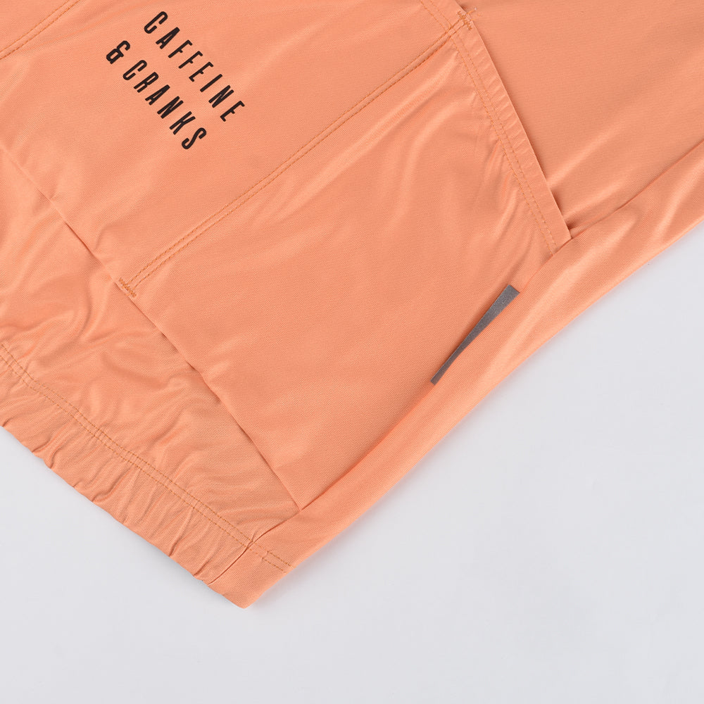 Close-up of orange women's Core Thermal Jersey, showing black text and pocket detail.