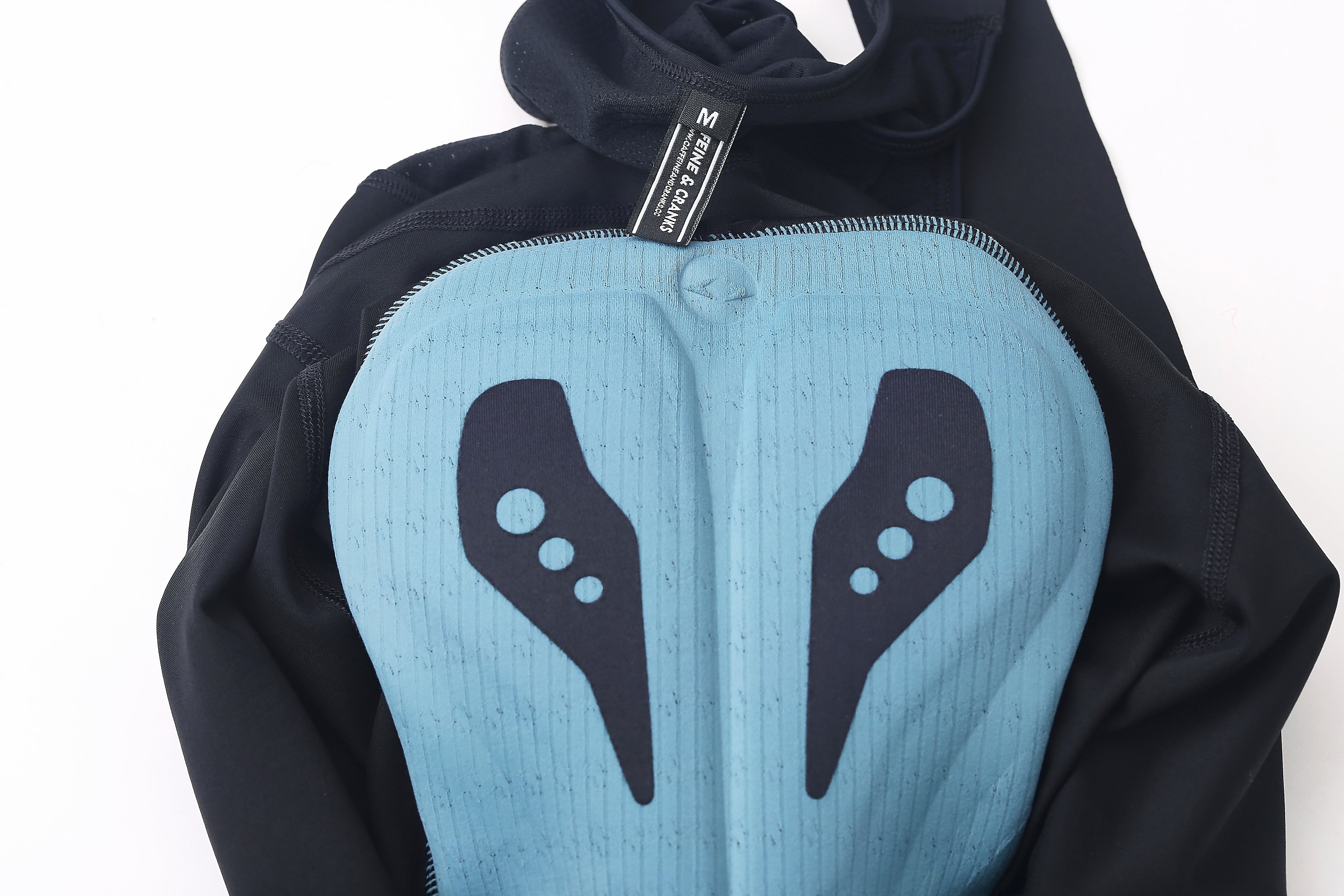 Close-up of women's bib shorts showing the padded blue chamois with black graphics and black outer fabric.
