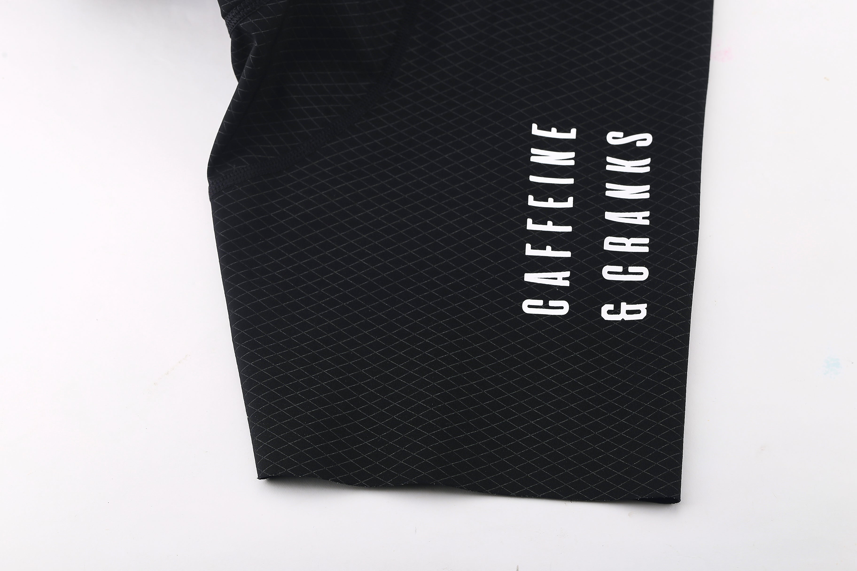 Close-up of the hem on black women's bib shorts with white text.