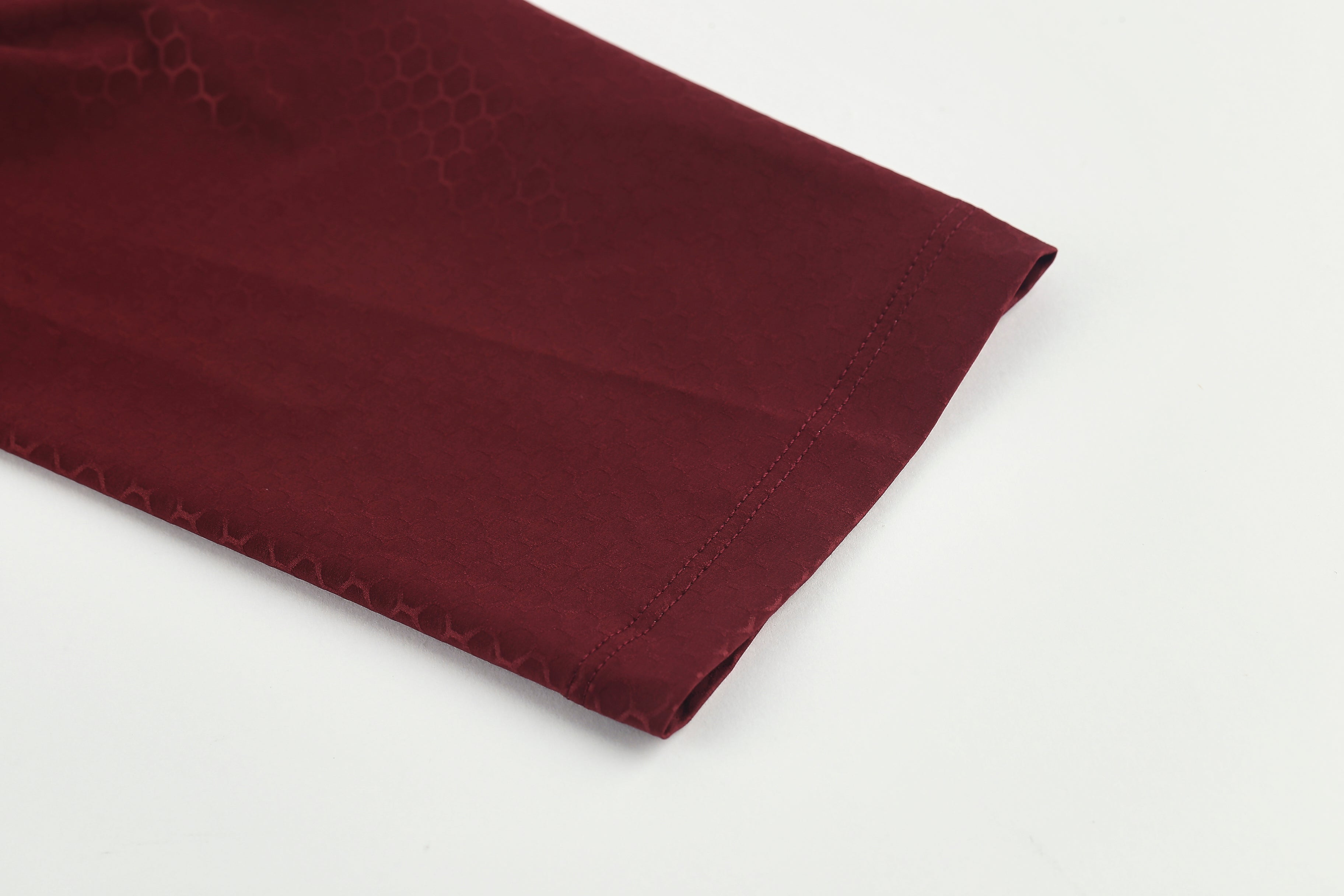 Close-up of wine red Pinnacle Jersey sleeve with subtle honeycomb pattern and double-stitched hem.