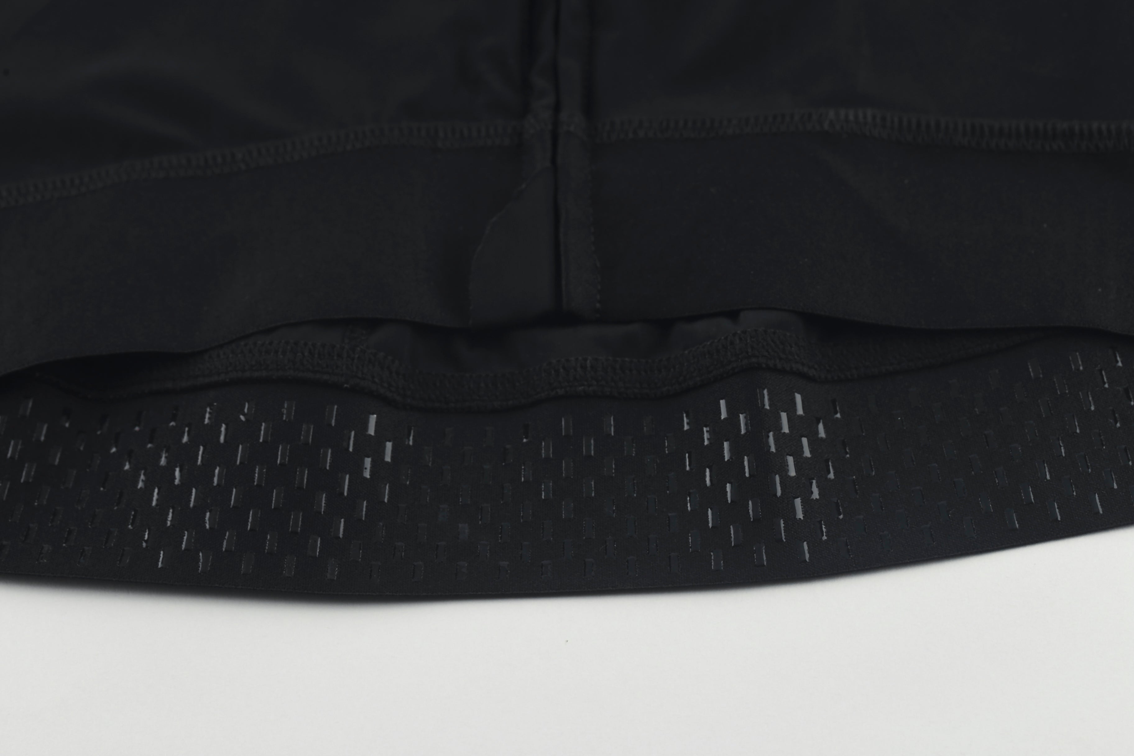 Close-up of the hem of a black men's cycling jersey with gripper details.