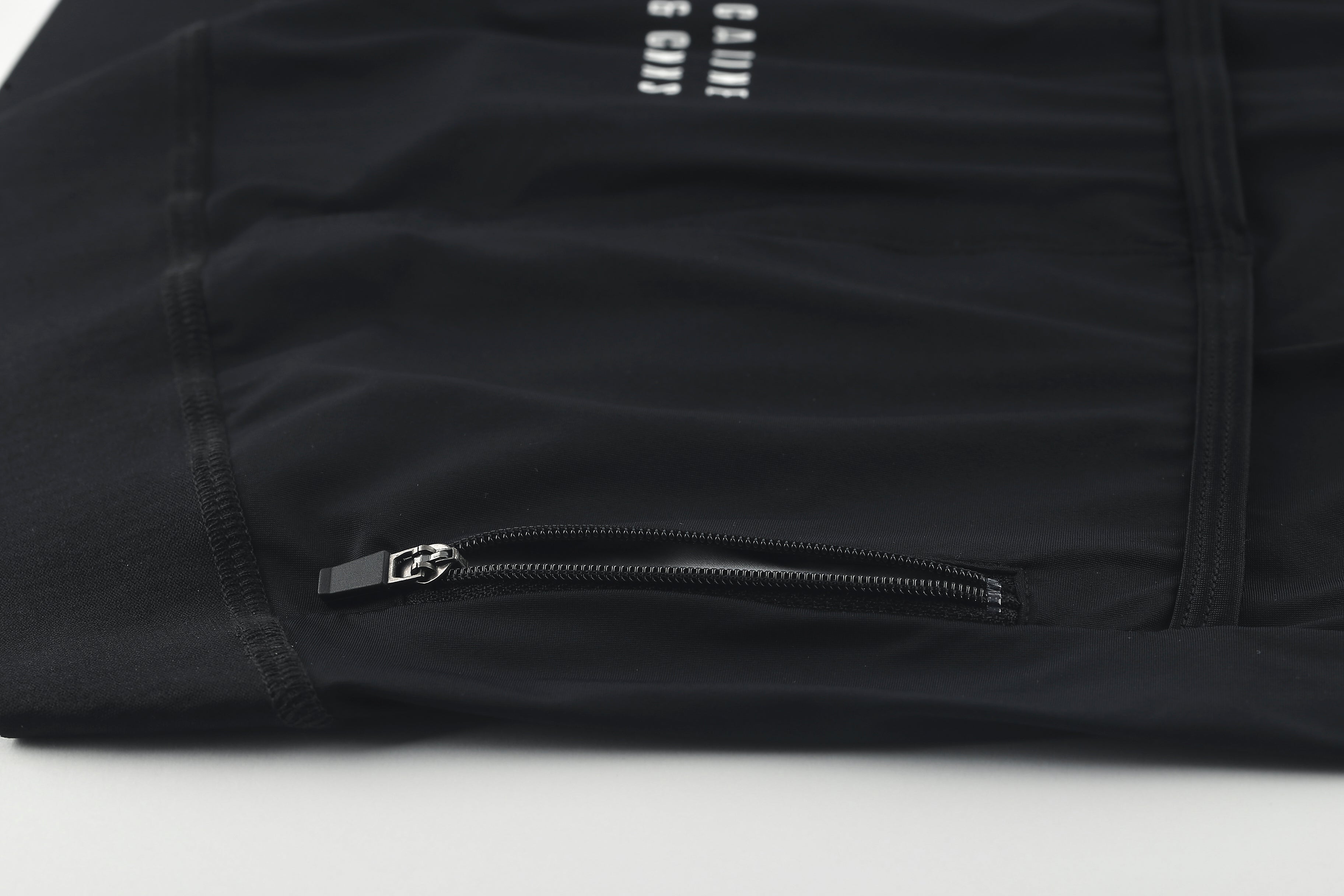 Close-up of a black women's jersey with a zippered pocket and silver hardware.