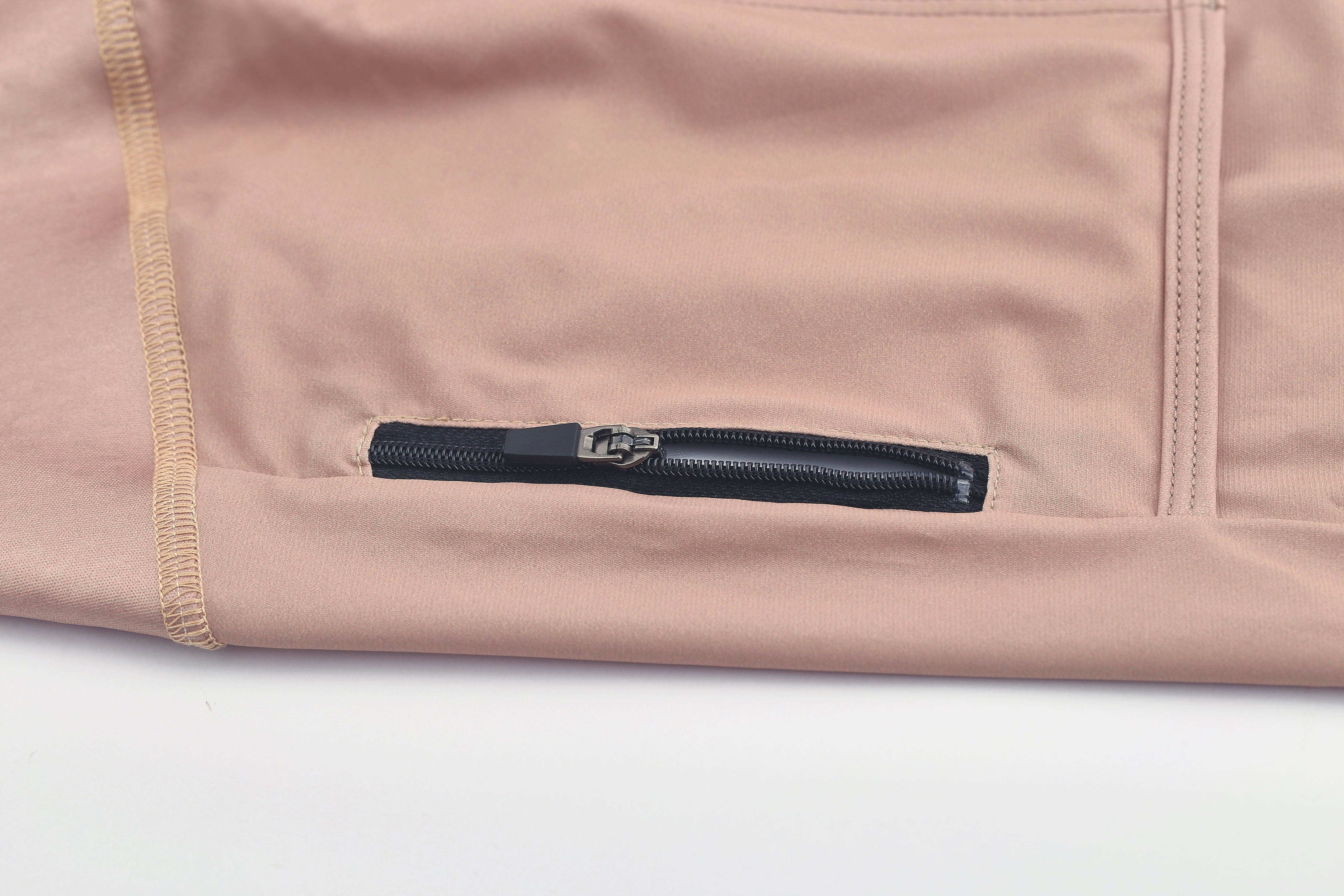 Close-up on a clay brown women's Pinnacle jersey, showing a black zipper pocket detail.