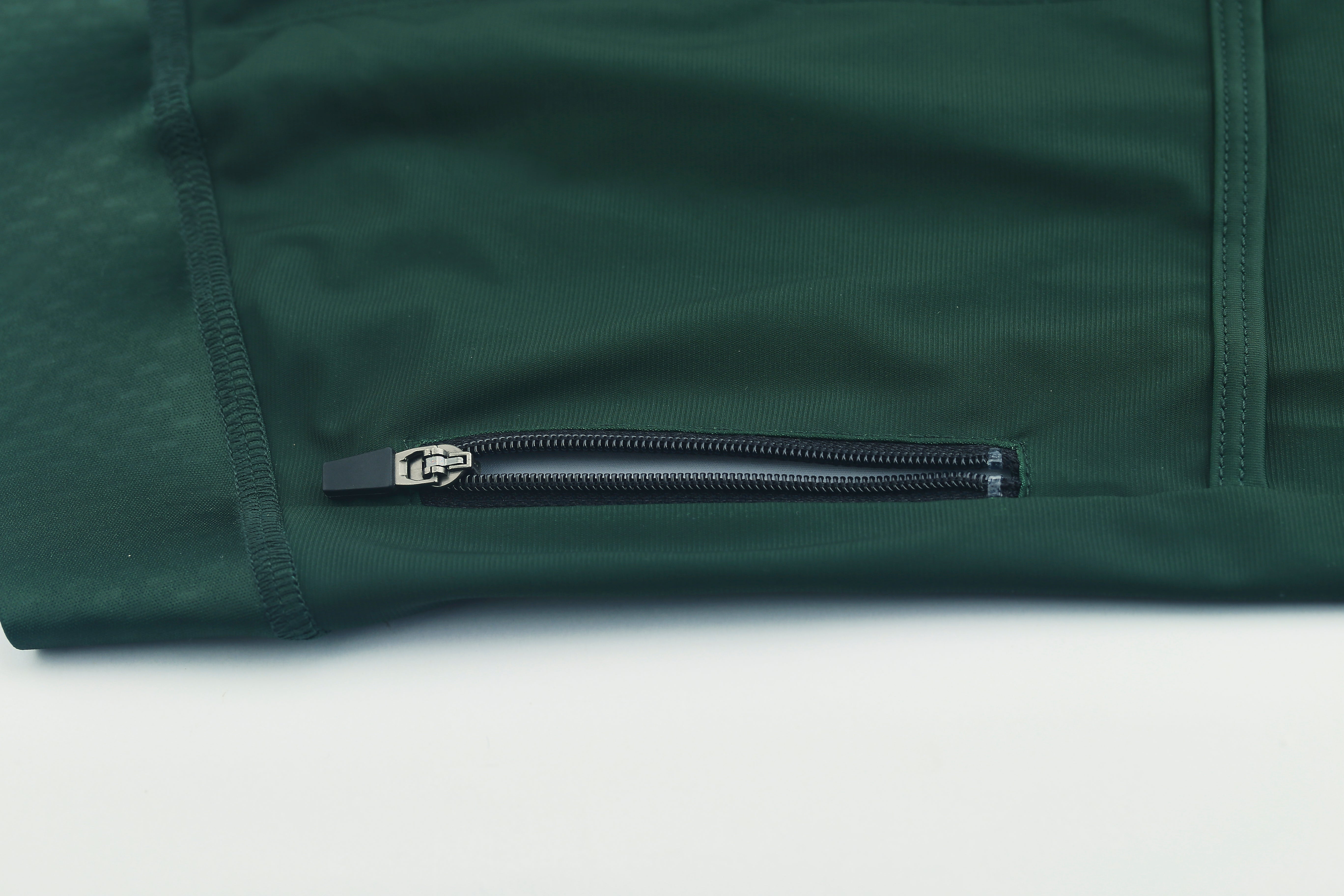 Close-up of a forest green men's Pinnacle jersey with a black zippered pocket.