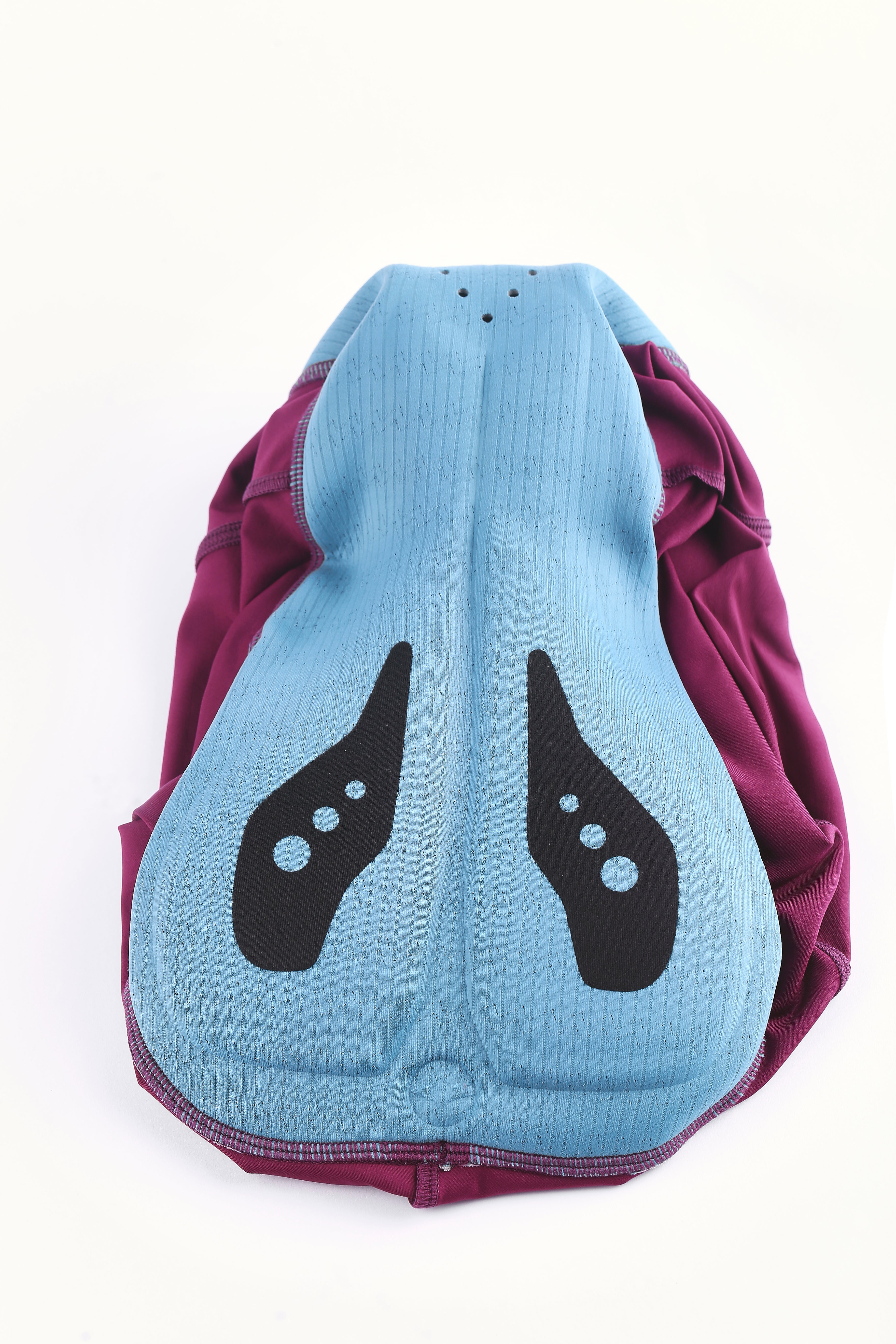 Close-up view of Pinnacle Bib Shorts mens padding in light blue with black accents and plum fabric.